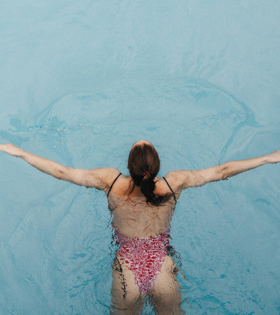 Frau schwimmt Bahnen im Außenpool vom Hotel Muhr