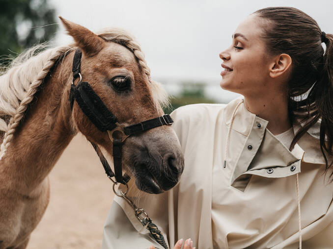 Dame streichelt Pferd im Hotel Muhr