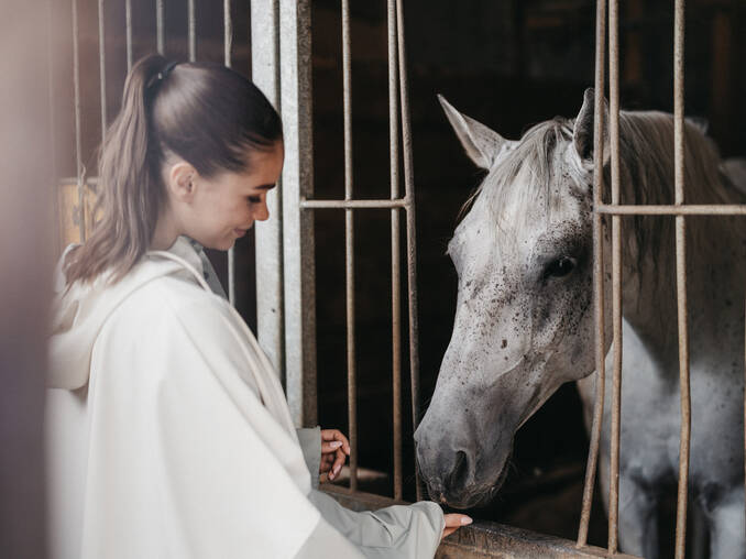 Frau füttert Pferd im Hotel Muhr